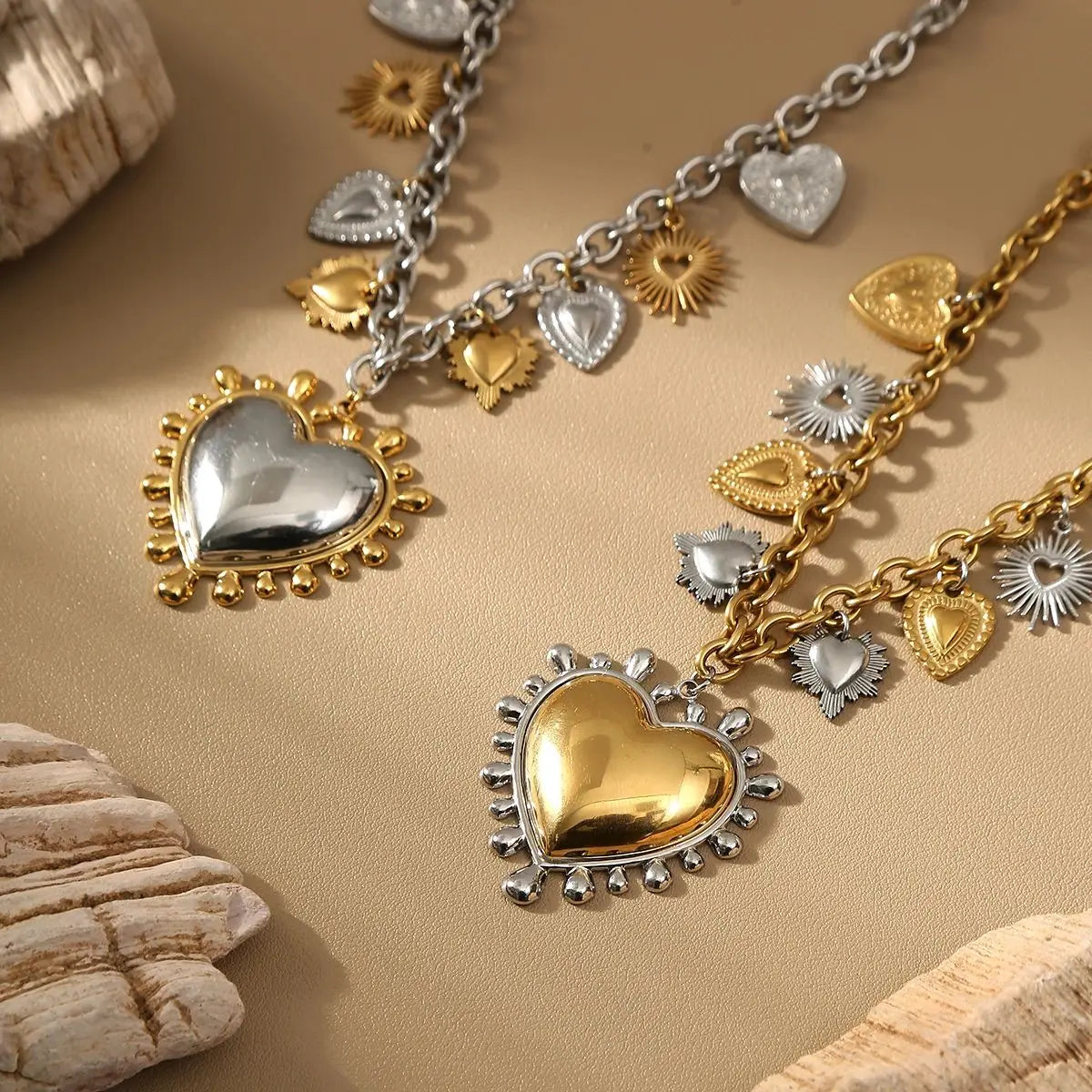 Gold and silver heart-shaped pendants on a beige surface with natural elements.