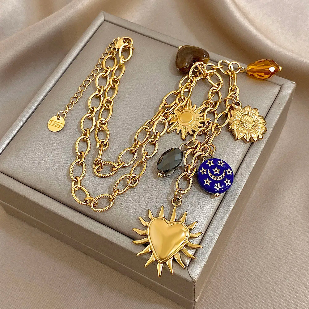 Gold necklace with various charms on a gray jewelry box