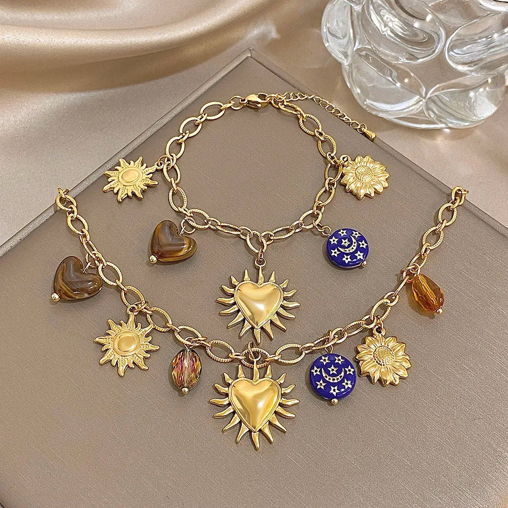 Gold charm bracelet with sun, heart, and star-shaped charms on a neutral background