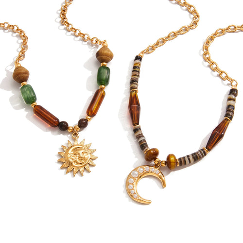 Necklace with sun and moon pendants and beaded chain on a white background