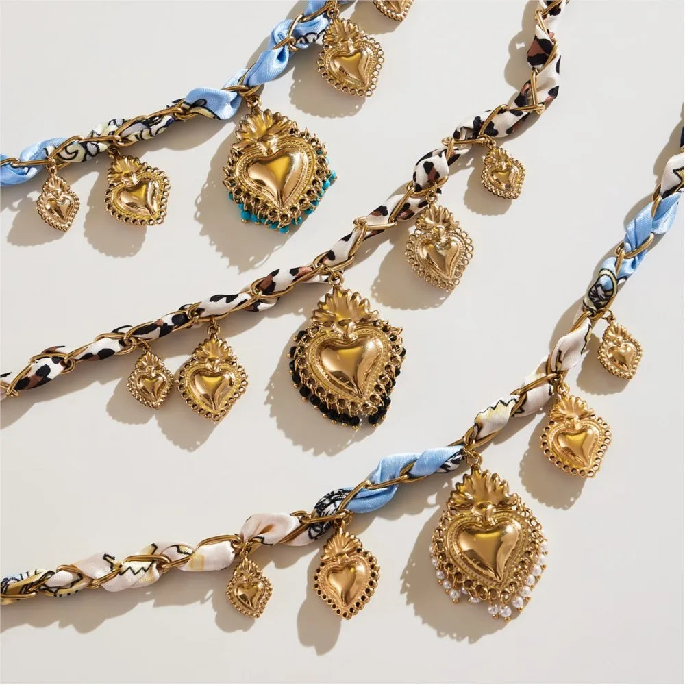 Gold heart-shaped charms on a chain with decorative links on a light background