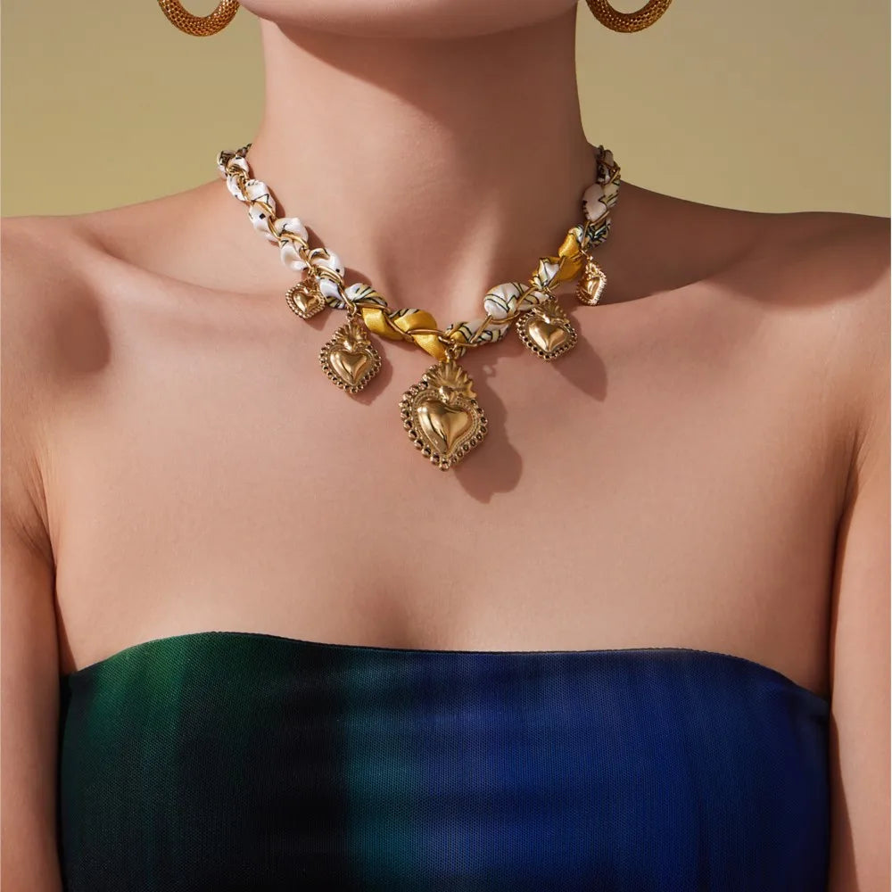 Gold necklace with heart pendants on a person wearing a green dress against a yellow background
