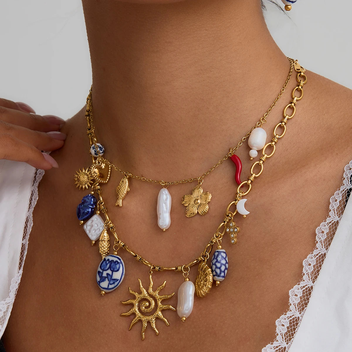Gold necklace with various charms worn by a person against a neutral background