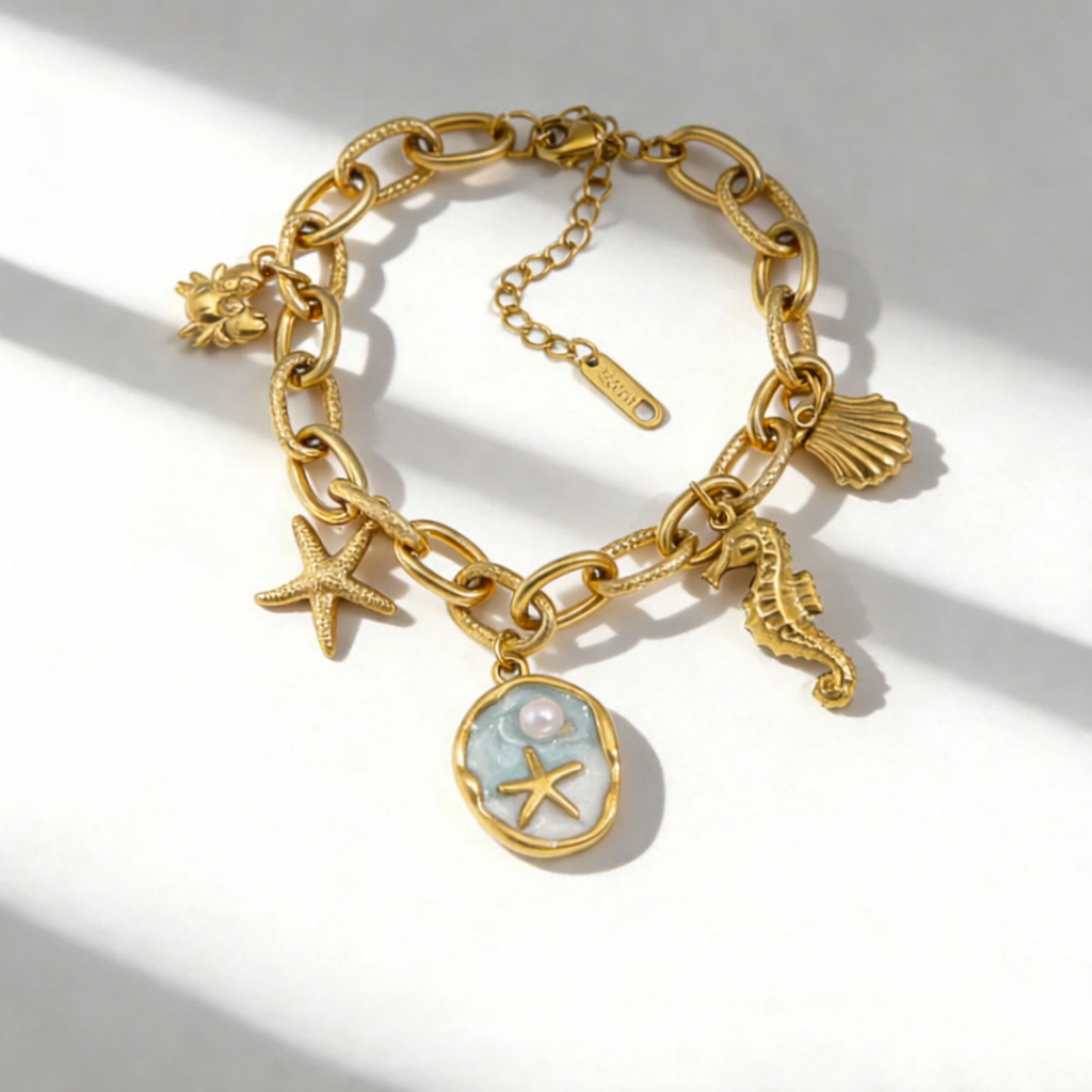 Gold chain bracelet with seashell, starfish, and seahorse charms on a white background