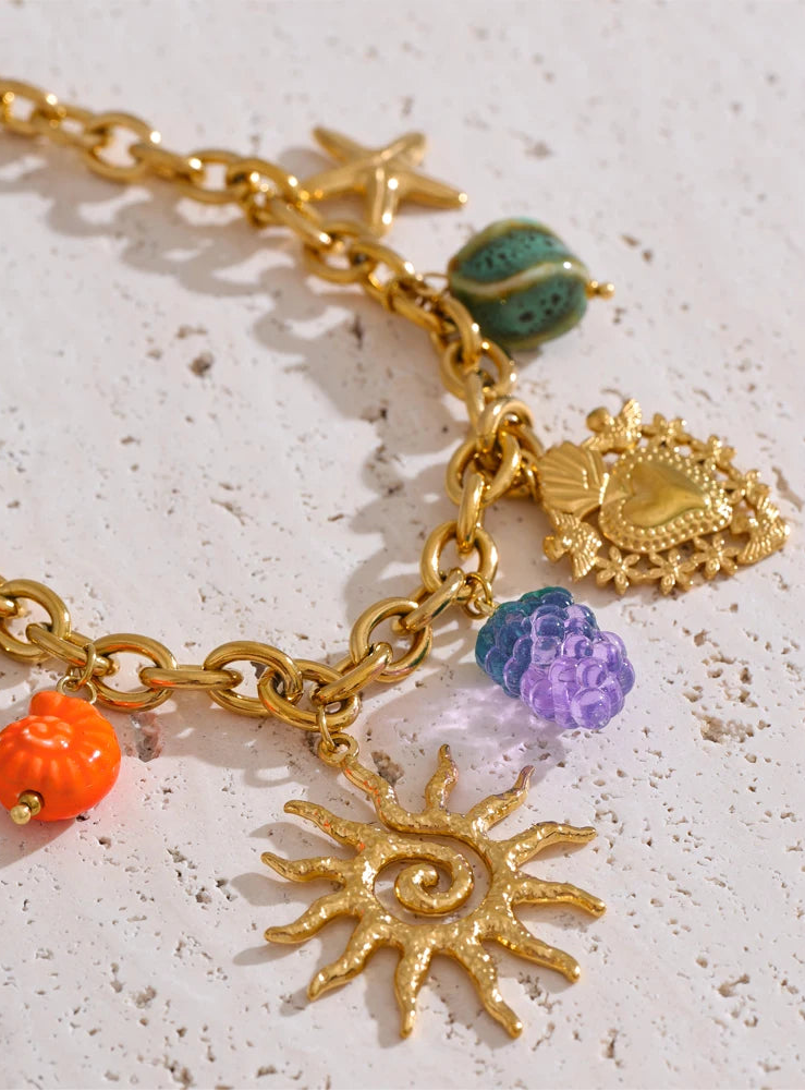Gold bracelet with various charms on a textured surface